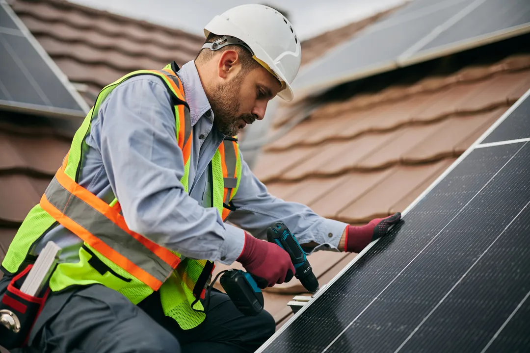 energía solar en México: Fotografía de un encargado de colocar los paneles solares arriba de una casa terminando la instalación