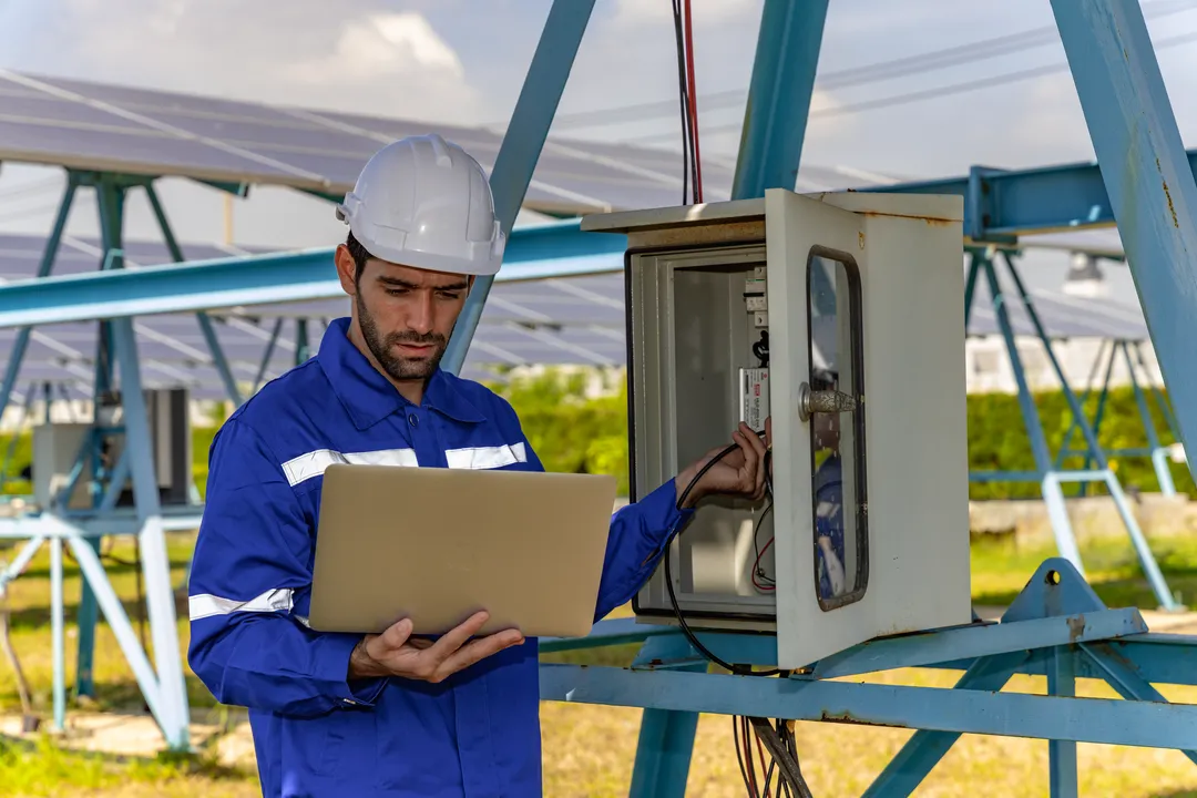 La energía solar para empresas es la mejor opción Fotografía de un encargado de medir los voltios de los paneles solares para usar la energía solar para empresas